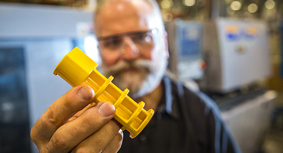 technician holding yellow injection molded part from Brazil Metal Parts